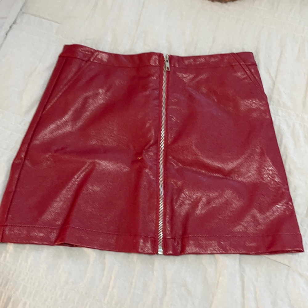Red pleather mini skirt with front zipper detail. Women’s size small.
